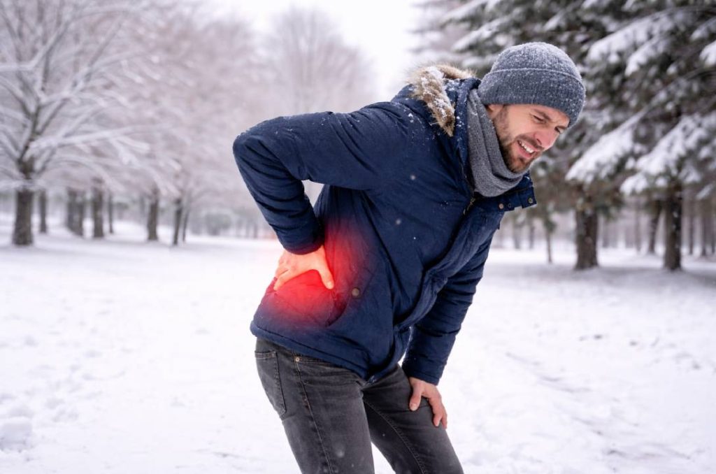 A man with bad winter back pain in a snowy forest