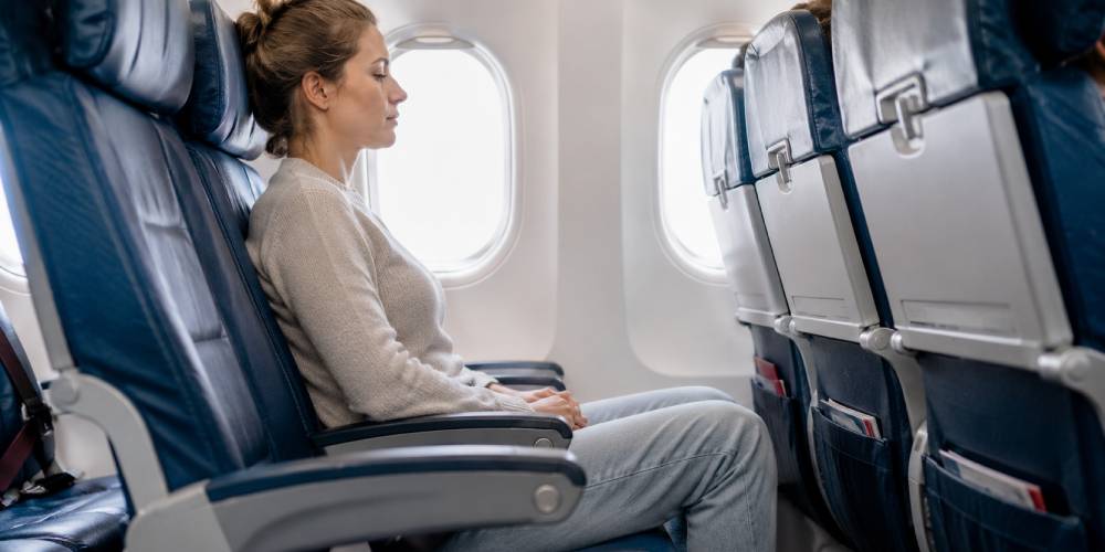 Woman sitting in an economy aeroplane seat with limited legroom during a flight